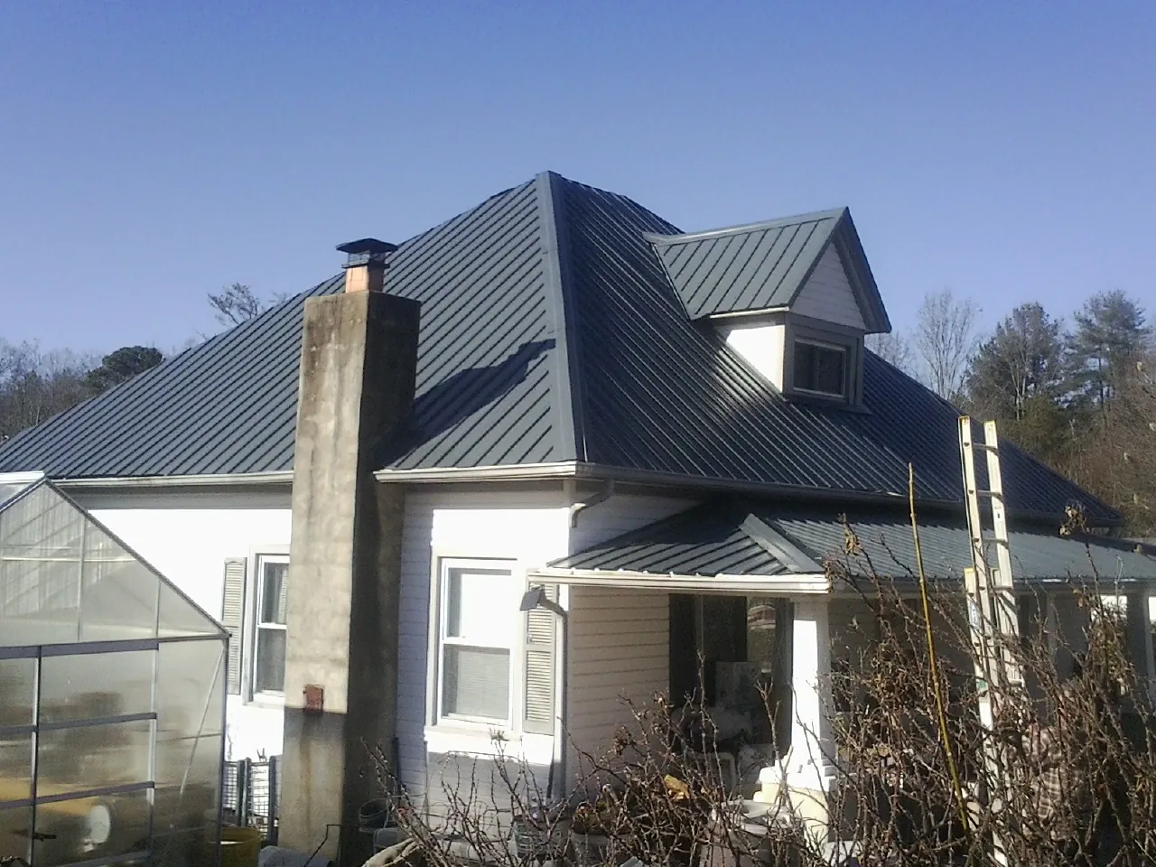 Dark blue standing seam metal roof on a white farmhouse with dormer — Slate & Tile Roof Repair by Roofing Brothers in Burket