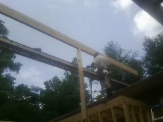 Carpenter setting a ridge beam over a new addition frame — Ice Dam Removal by Roofing Brothers in Burket