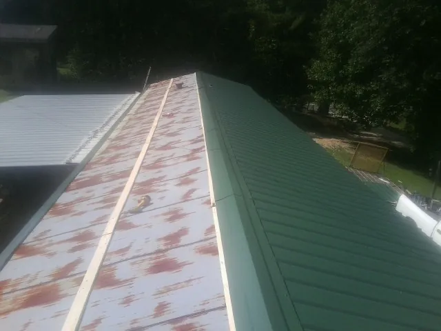 Old rusted panels beside newly installed green metal roofing — Wind Damage Roof Repair by Roofing Brothers in Burket