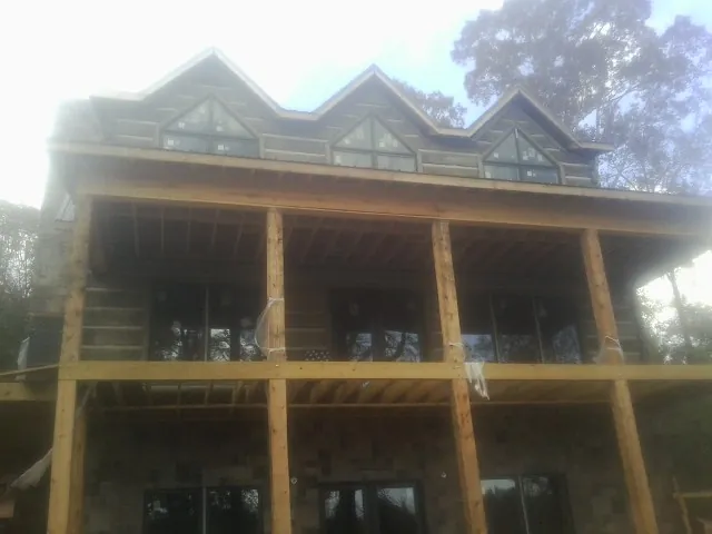 Dormers and porch framing on a large log home under construction — Roof Coating work by our crew in Burket