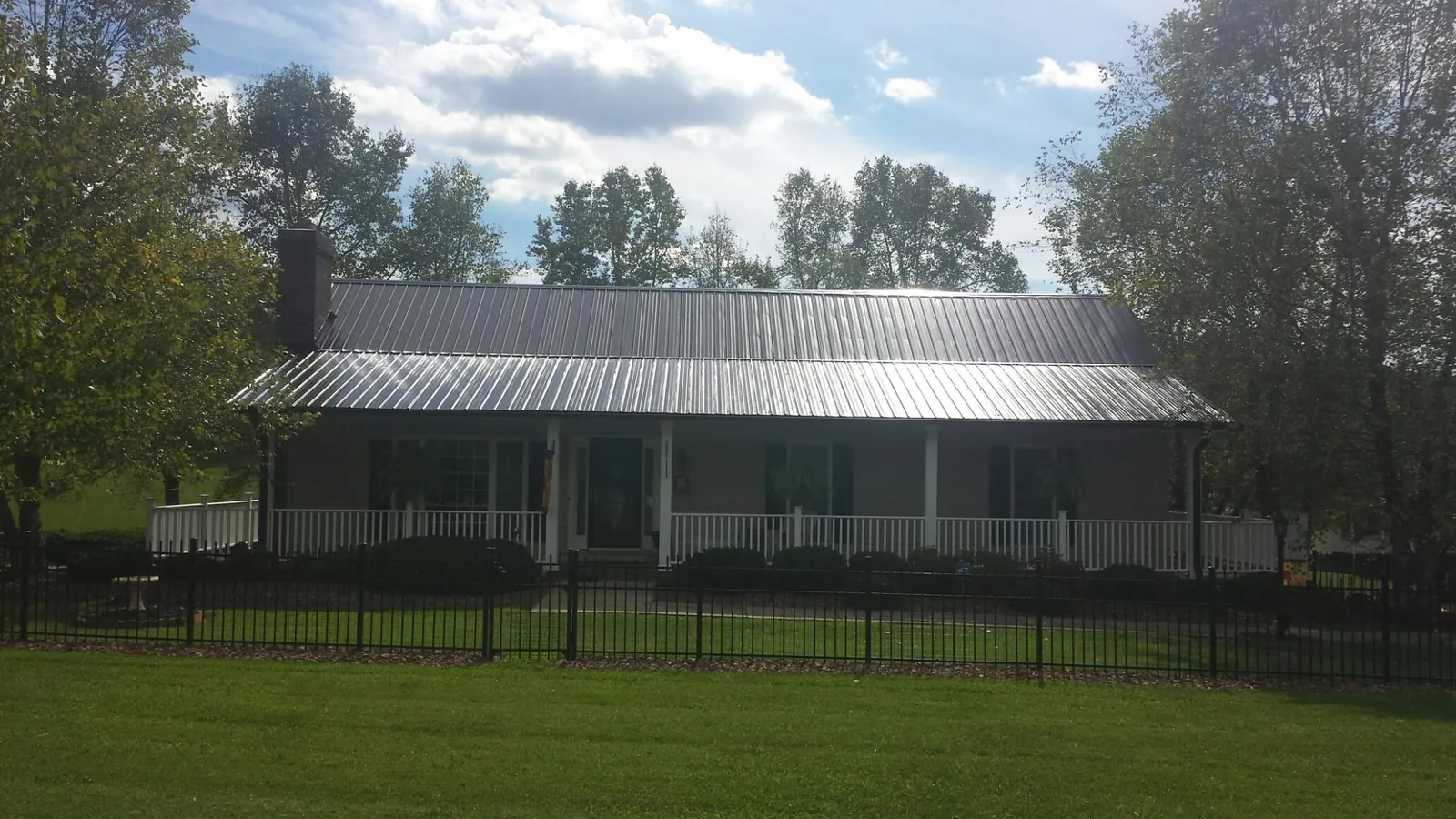 Gray metal roof on a brick ranch with a full width front porch — Gutter Guard Installation work by our crew in Burket