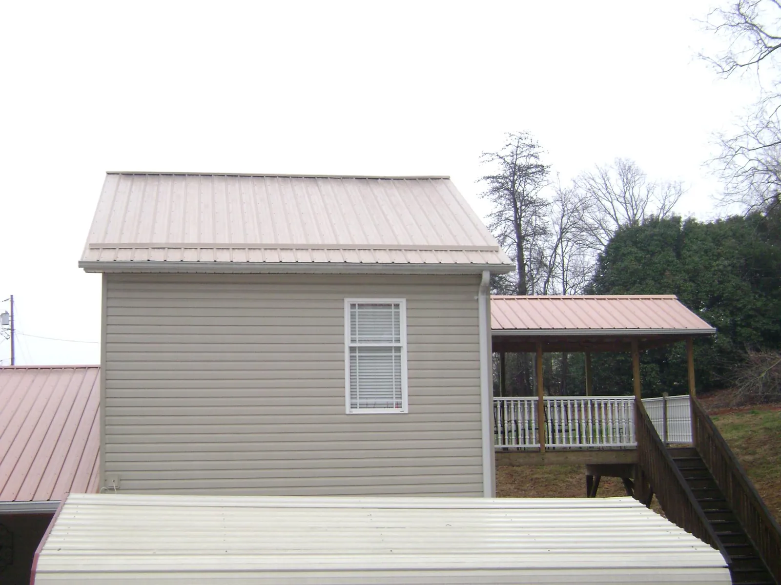 Tan metal roofs on a two story addition and attached porch, from a Roof Replacement job in Burket