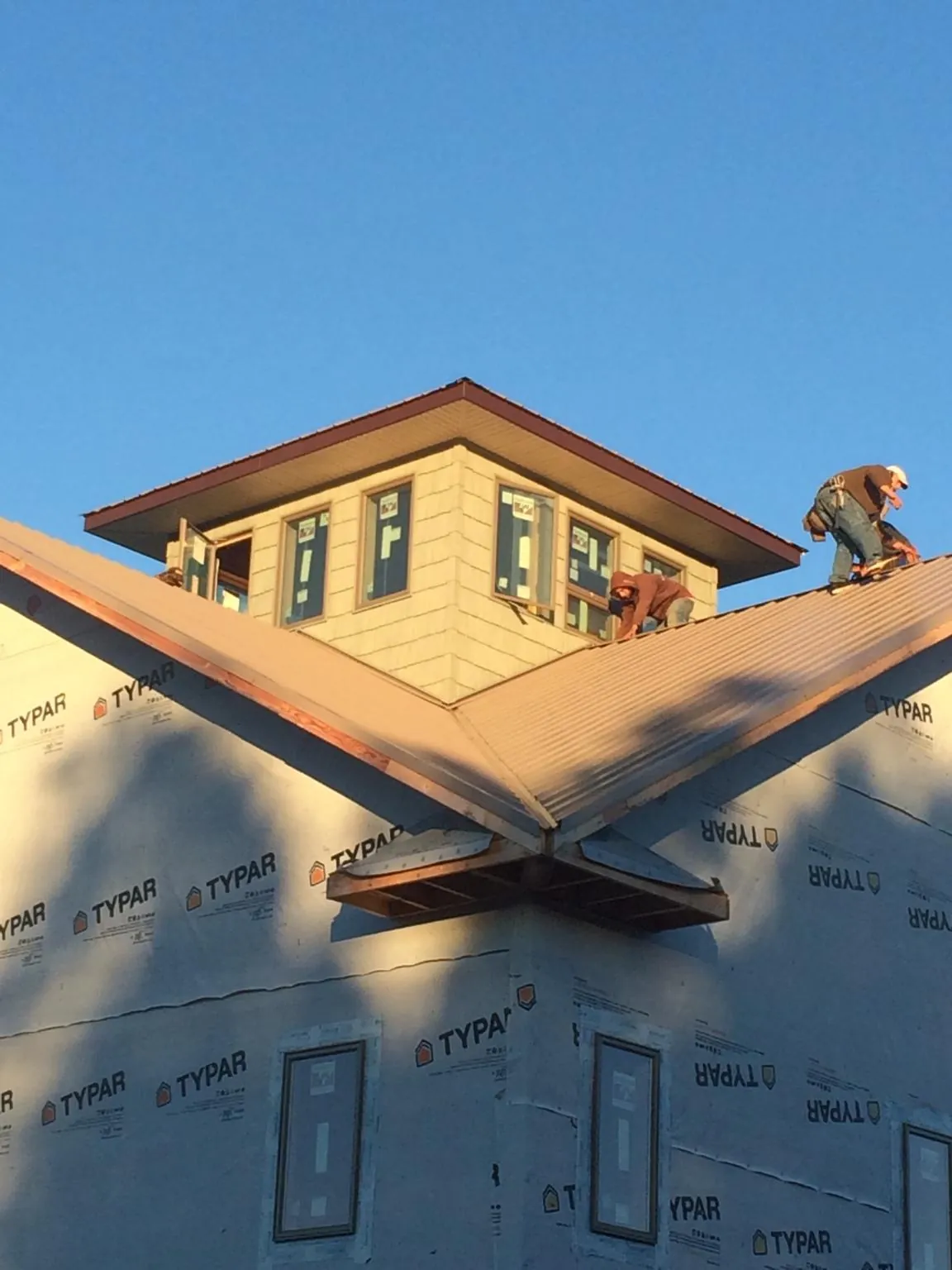 Roofers working around a rooftop cupola on a new metal roof at sunset — Roof Waterproofing in Burket by Roofing Brothers